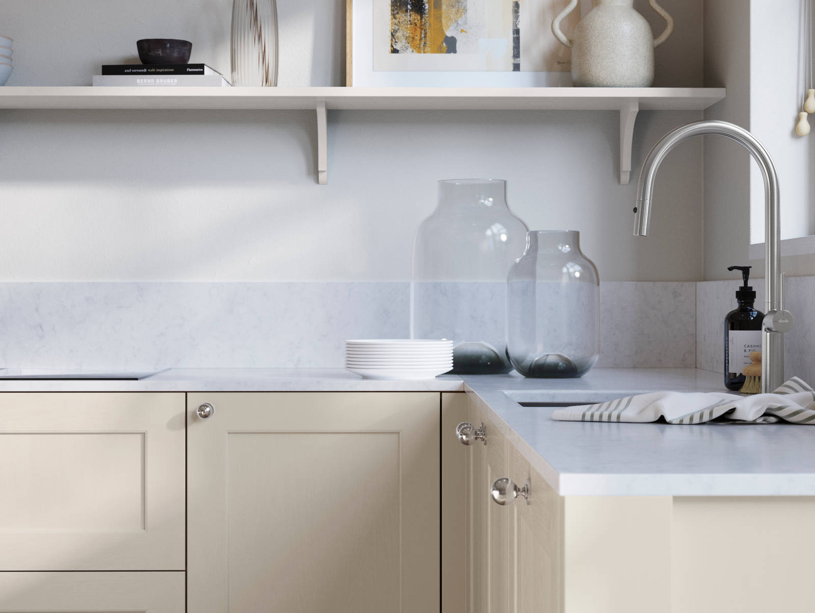 Ludlow, a traditional Shaker-style premium feel kitchen range with a visible woodgrain on its panelled doors here shown in the light shade limestone styled with steel knobs, steel tap, a white marbled worktop with matching splashback.