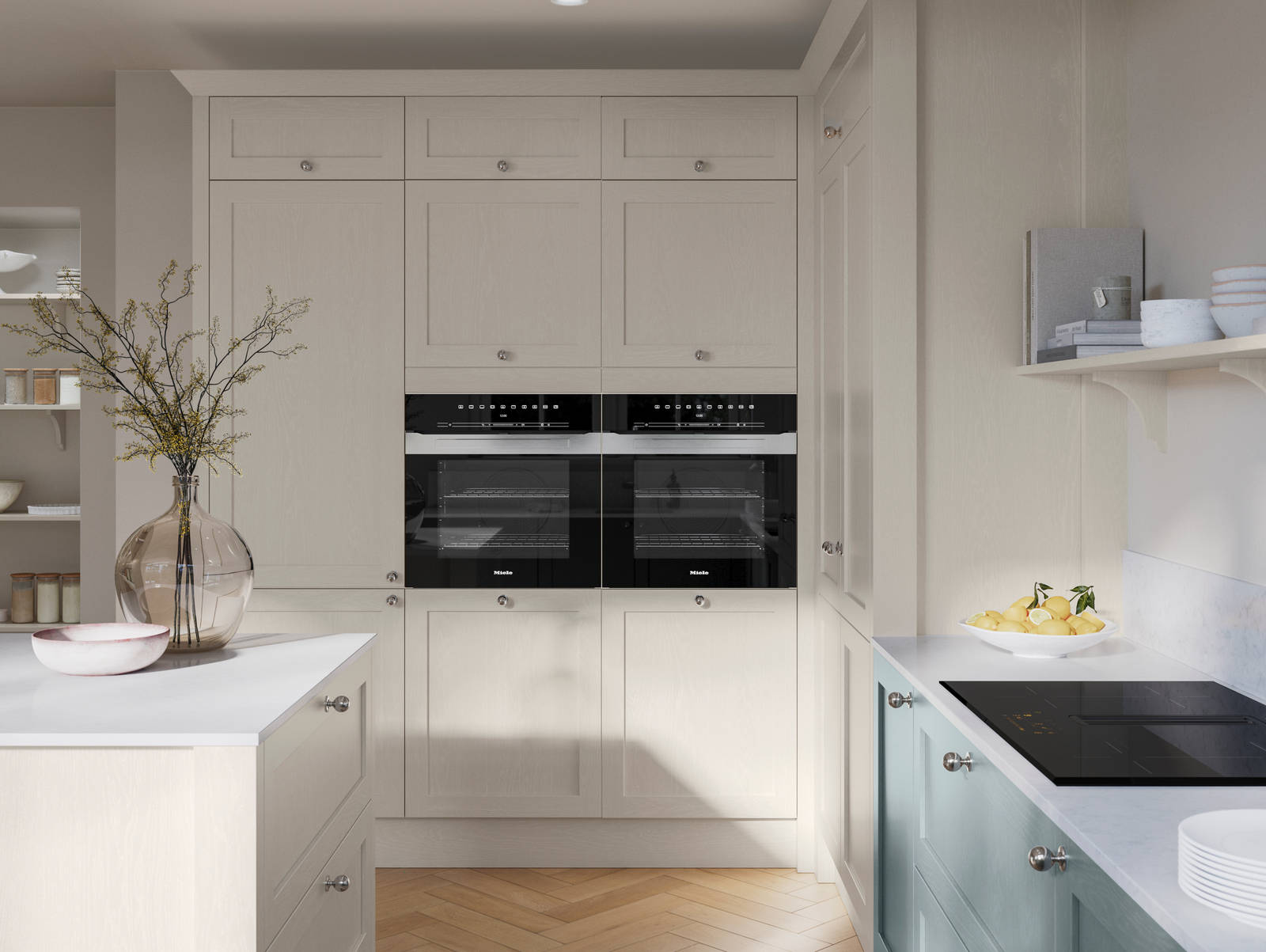 Tall Wardley Limestone cabinets with built-in ovens, steel knob handles, a white countertop on Limestone shade kitchen island and blue Duck Egg cabinets with induction hob.