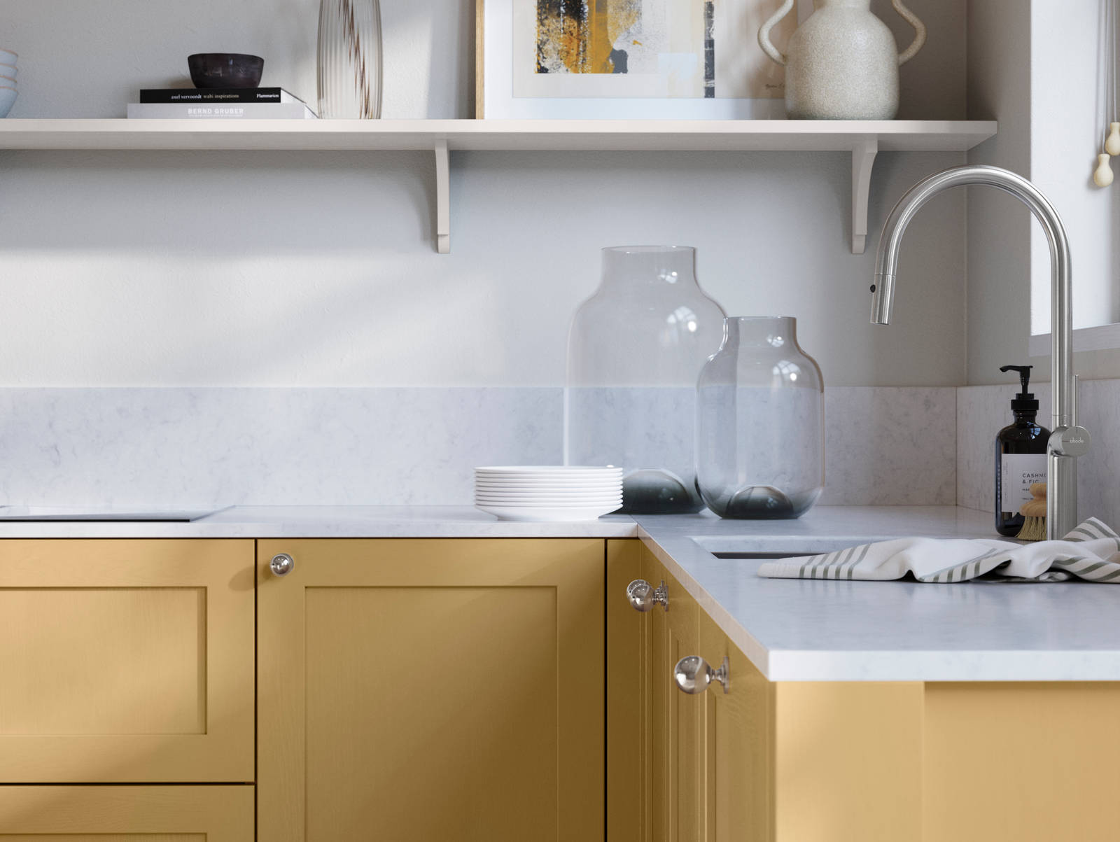 Wardley Harvest kitchen cabinetry with steel knobs, steel tap, white marbled worktop and matching backsplash. An open shelf on the wall above cabinets with ceramics and a vase of flowers.