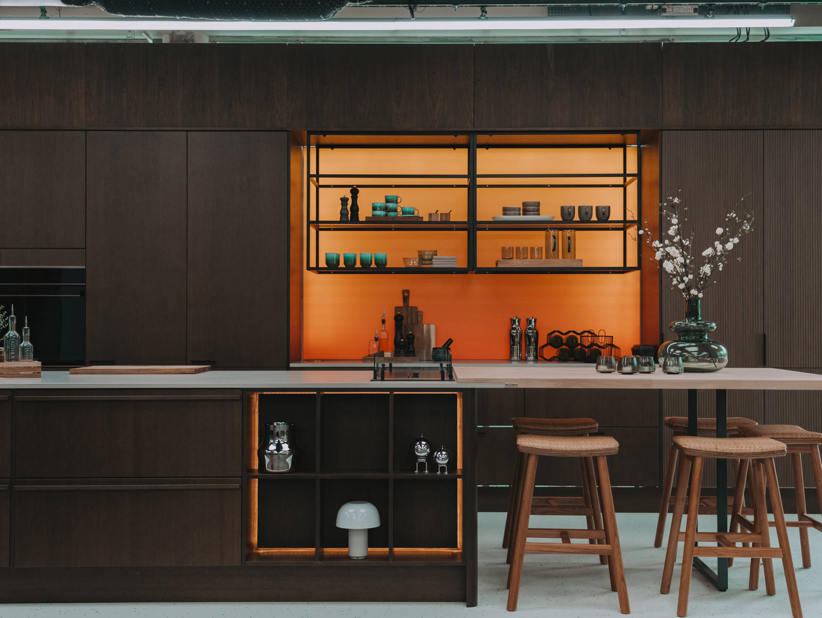 Kjøkken i modell Favn fra Sigdal i lekker eikefinér, som er beiset i fargen Nøtt, kjøkkenøya med barkrakker og åpne hyller i sort metallramme i God Morgen Norge studion sin