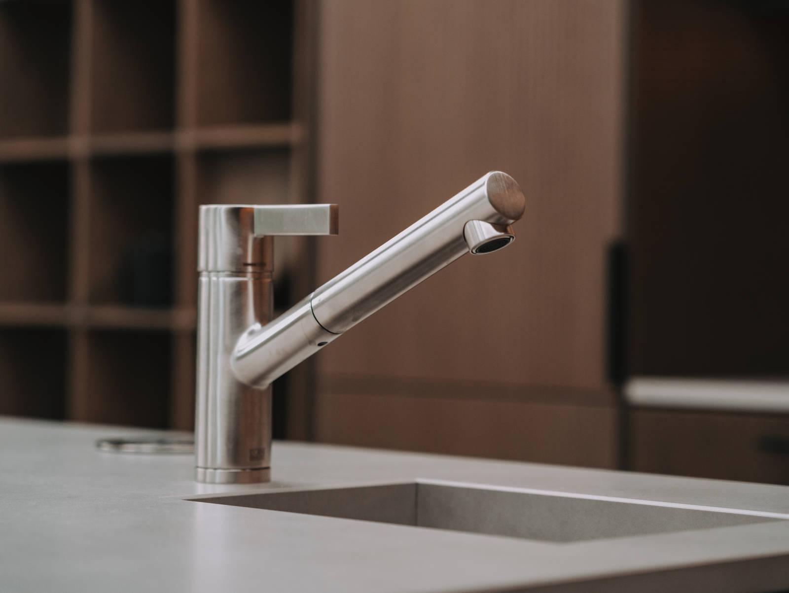 Nærbilde av kran og vask i kjøkkenøya Favn Nøtt i lekker eikefinér fra Sigdal med benkeplate Neolith i God Morgen Norge studion sin