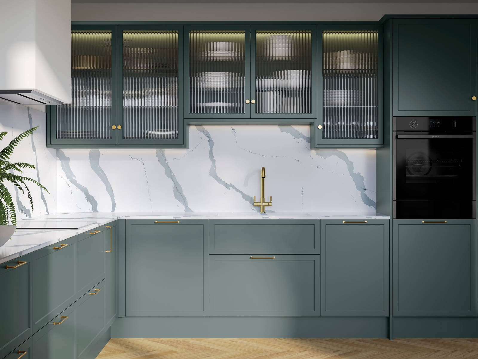 Modern Shaker kitchen Brunswick Spruce, a muted green shade, wall cabinets with fluted glass doors, Quartz Bianco Calacatta worktop and splashback, brass accessories like knobs, handles and tap, and a light wood herringbone floor.