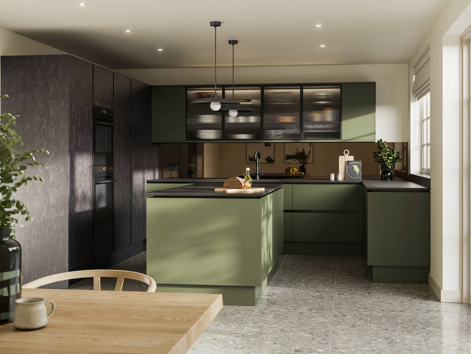 Integra Soho Tailored Green kitchen and kitchen island with contrasting dark wood Portobello Etna, black accessories, integrated ovens in tall cabinets, Dekton worktop and fluted glass vitrin wall cabinets with wood dining room table in foreground.