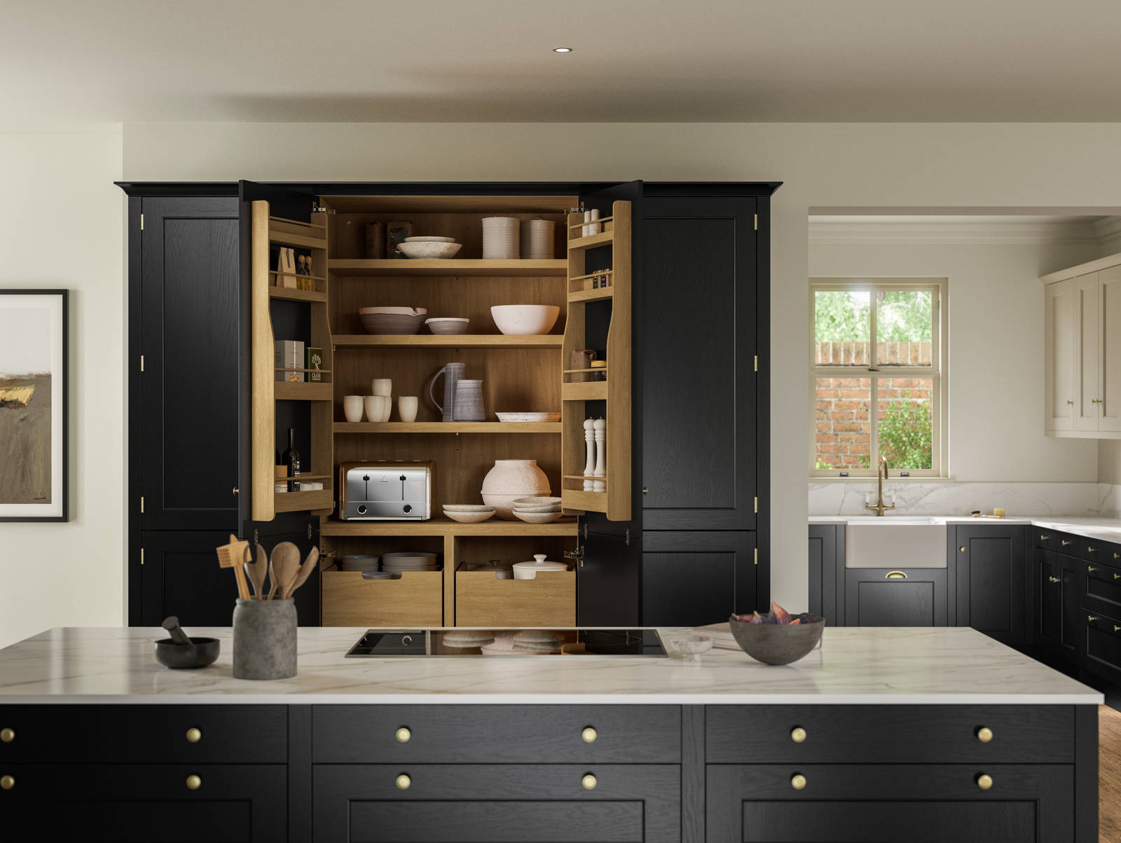 View over kitchen island in Traditional Shaker-style tactile woodgrain Ludlow Sumi Black kitchen, opened tall oak larder cabinets, brass accessories, marbled white and grey worktop, white ceramic sink and brass tap.