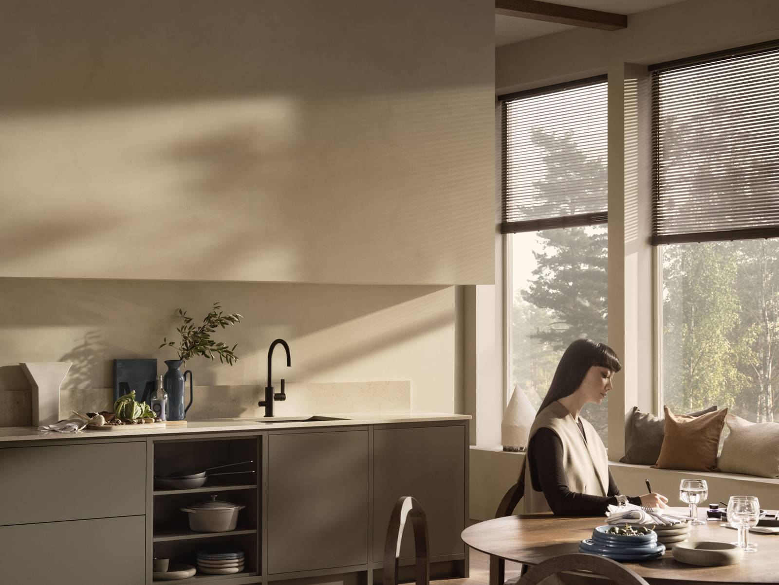 En kvinna sitter vid ett köksbord i ett Warm Minimalism Marbodalkök.