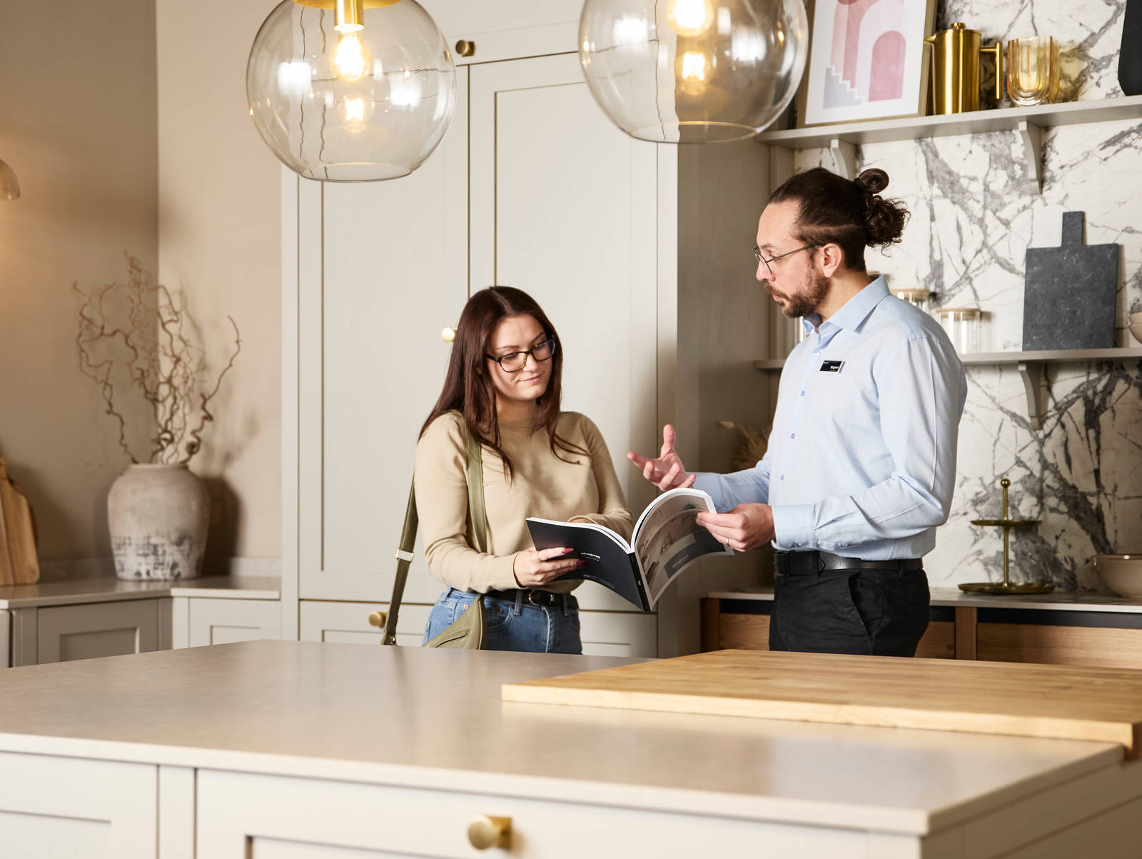 Woman and kitchen designer looking at and discussing a brochure in Shaker style kitchen at a Magnet Showroom.
