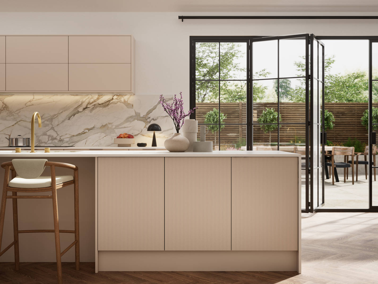 Fluted front kitchen Reed from Magnet in light warm neutral shade Shell, with a marbled splashback, worktop and decorative side on kitchen island with barstools and black handles, herringbone wood flooring.