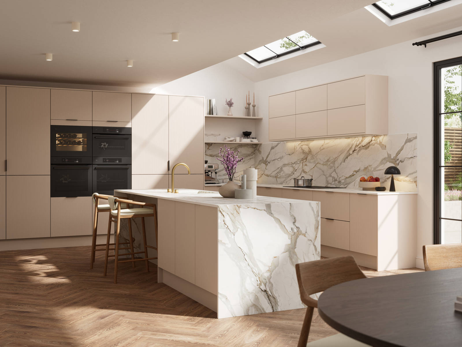 Fluted front kitchen Reed from Magnet in light warm neutral shade Shell, with a marbled splashback, worktop and decorative side on kitchen island with barstools and black handles, herringbone wood flooring.