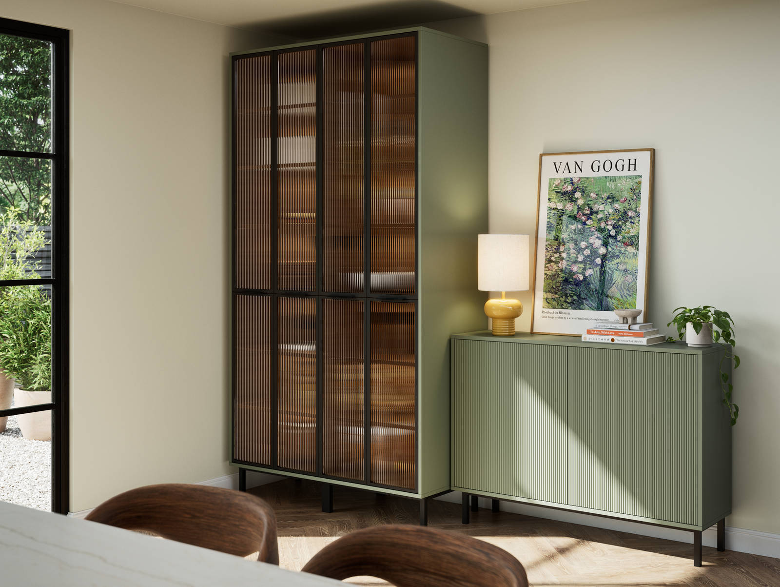 Vitrine with fluted glass in black metal frames, on green cabinet next to green fluted kitchen fronts on sideboard cabinets on black metal legs.