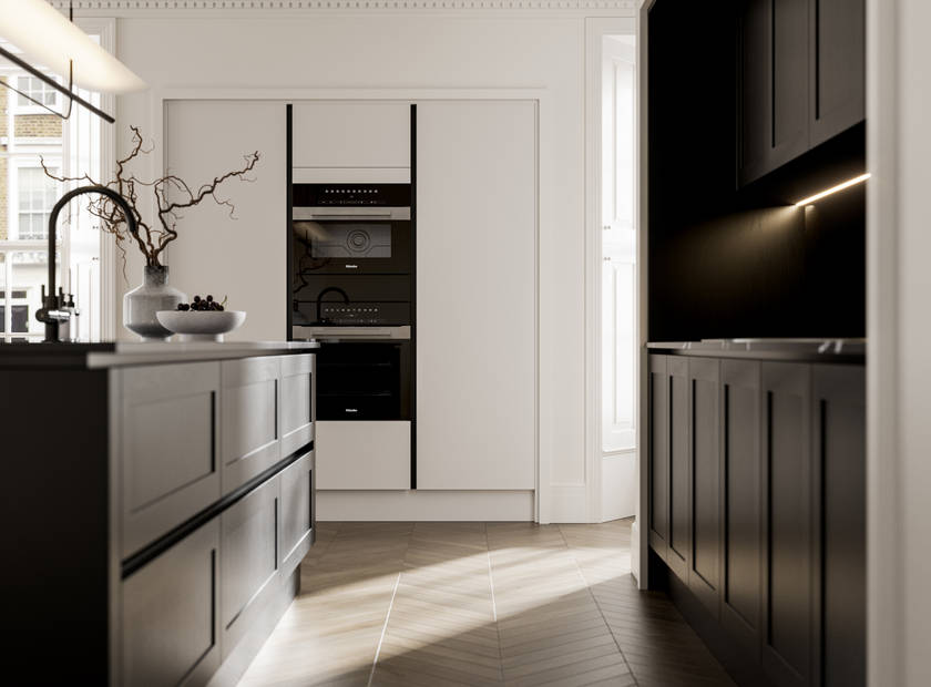 Handleless frame doors Integra Wardley Sumi black kitchen and kitchen island, Integra Soho Limestone tall cabinets with integrated ovens, natural shade ceramic vase holding foliage branches.