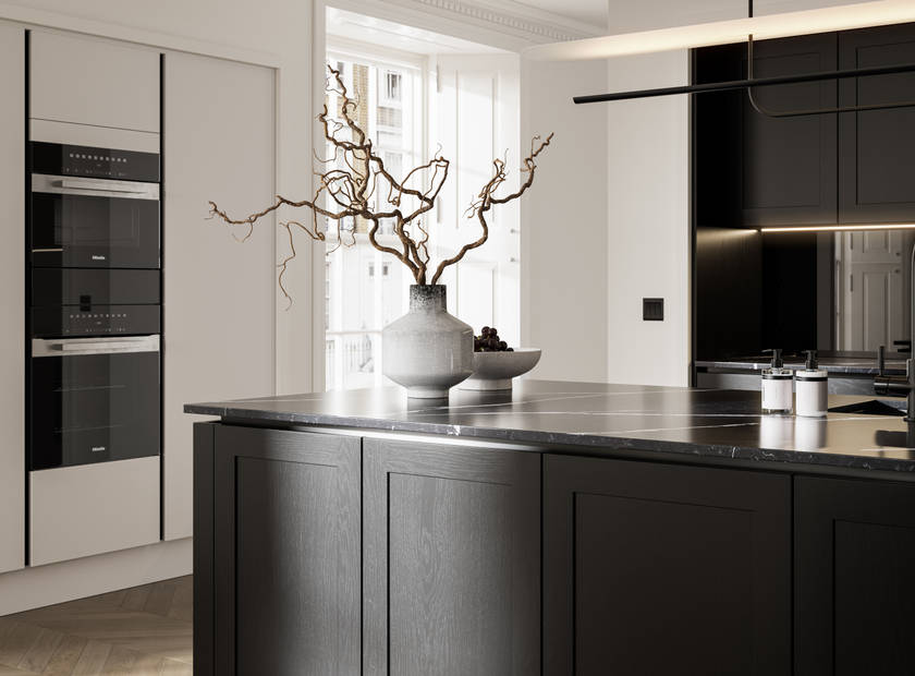 Handleless frame doors Integra Wardley Sumi black kitchen with kitchen island, Integra Soho Limestone tall cabinets with integrated ovens, natural shade ceramic vase holding foliage branches.