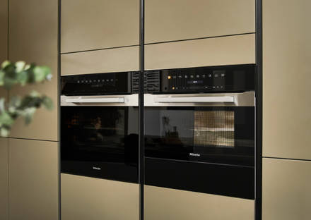 Built-in Ovens in modern slab front Balmoral Soho cabinetry from Magnet, Dekton in Ceppo worktop of kitchen island in foreground.