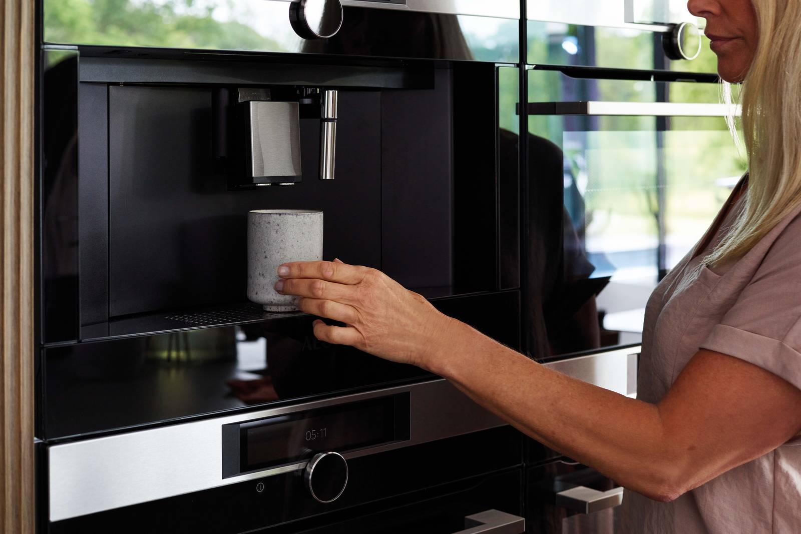 Woman using the integrated coffee machine in a Nordic Nature kitchen from Magnet