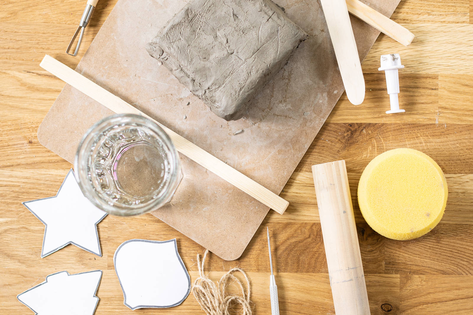 A block of clay on a wood board, with clay tools around it.