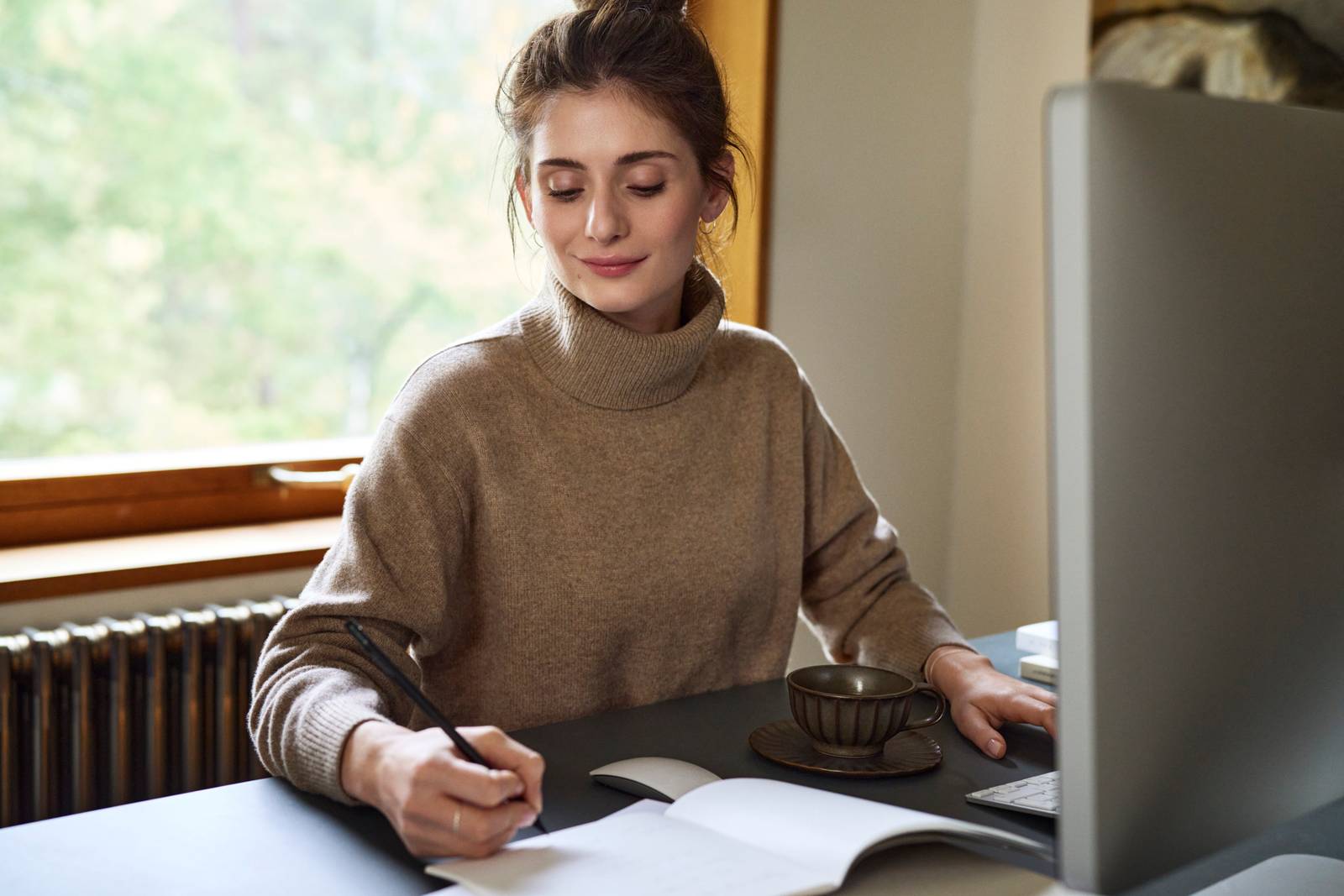 Kvinde gør anteckning framfør computeren