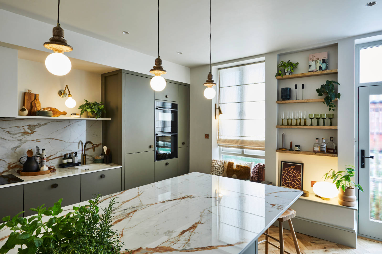View over kitchen island of modern slab Soho cabinets in the Balmoral colour, a soft beige green tone