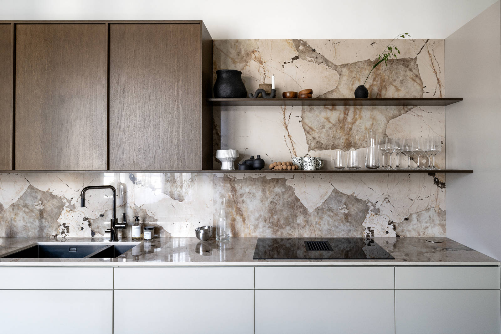 Køkken med en kombination af køkkenbord i beige Athena Sand med overskabe i Forever Oak fineret egetræslåge i brunbejdset fra INVITA, bordplade og stænk, der matcher, og åbne væghylder i brunbejdset eg finer.