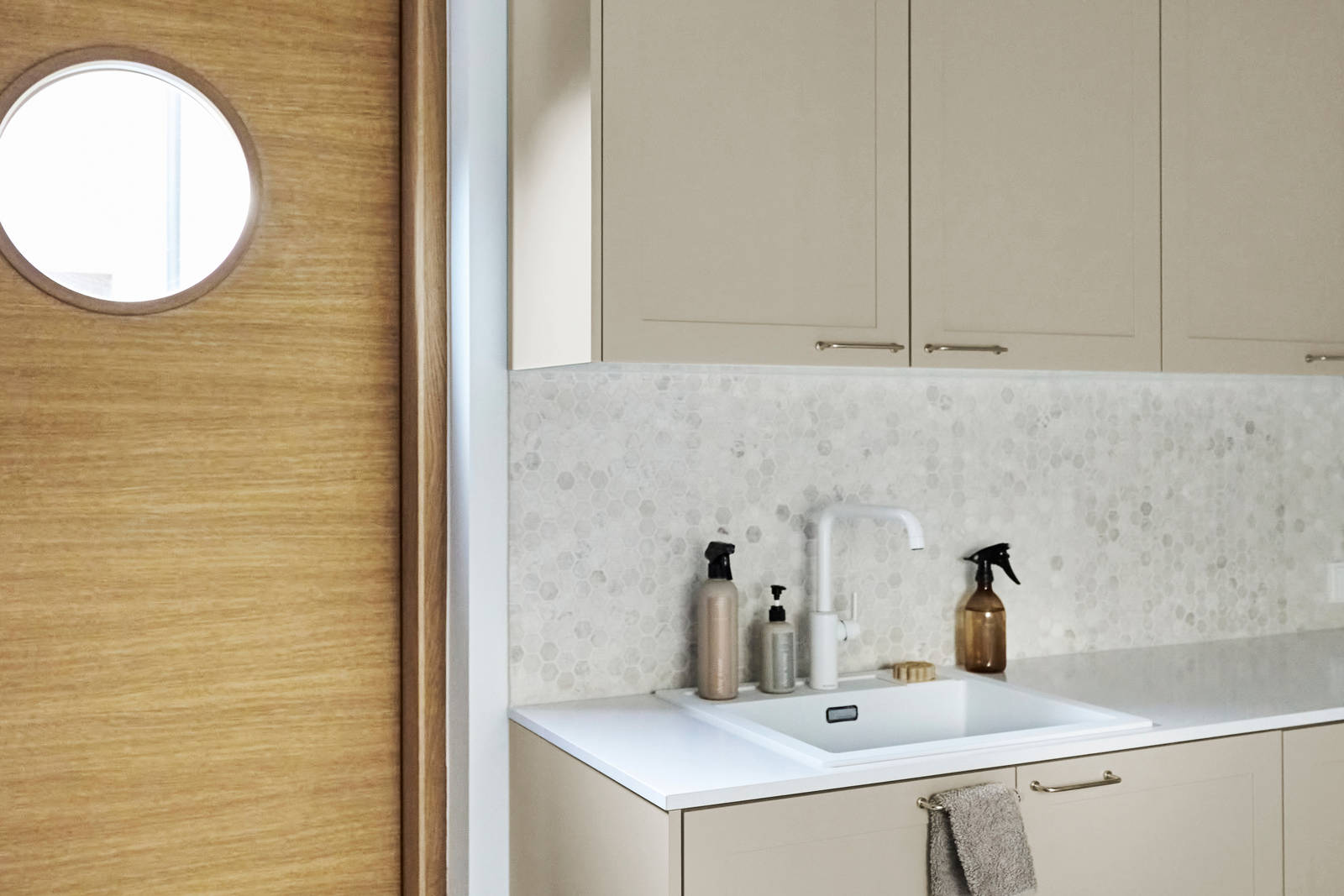 Beige-kaapit Novartilta ja harmaa marmorinen työtaso kodinhoitohuoneessa