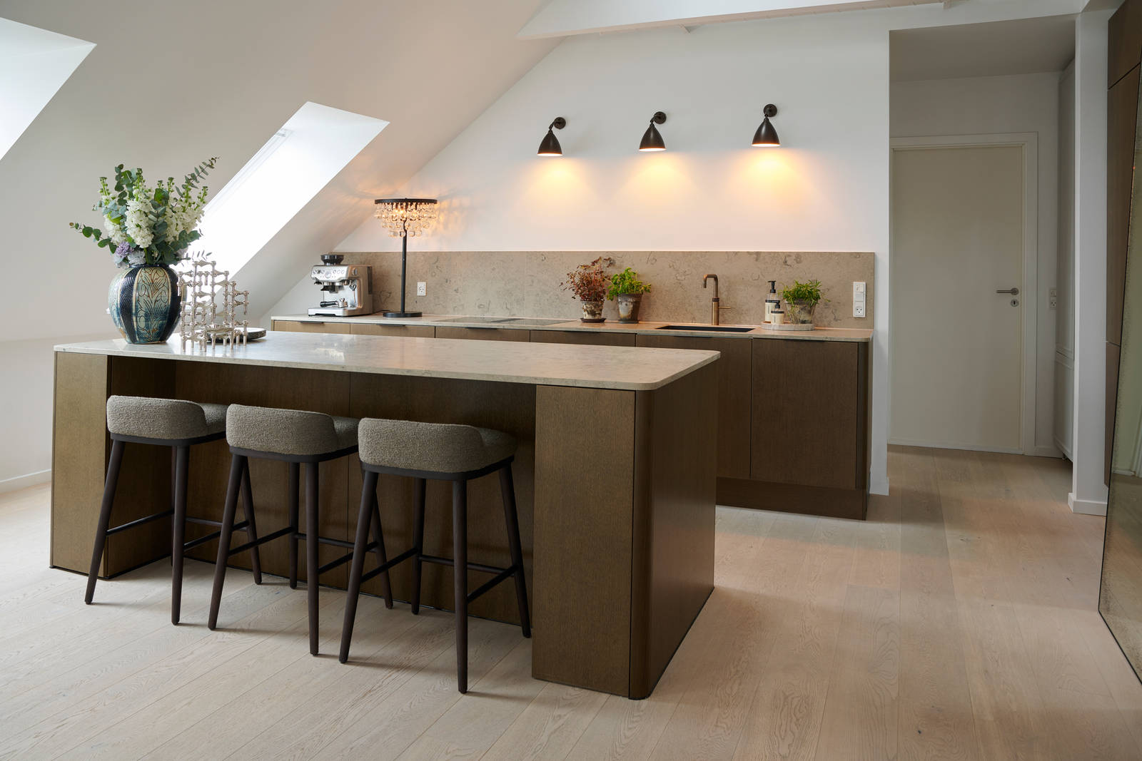 Signatur Ekbacken-kök med köksö, mörka träfronter, bänkskiva och stänkskydd i marmor, svart handfat och mässingsblandare