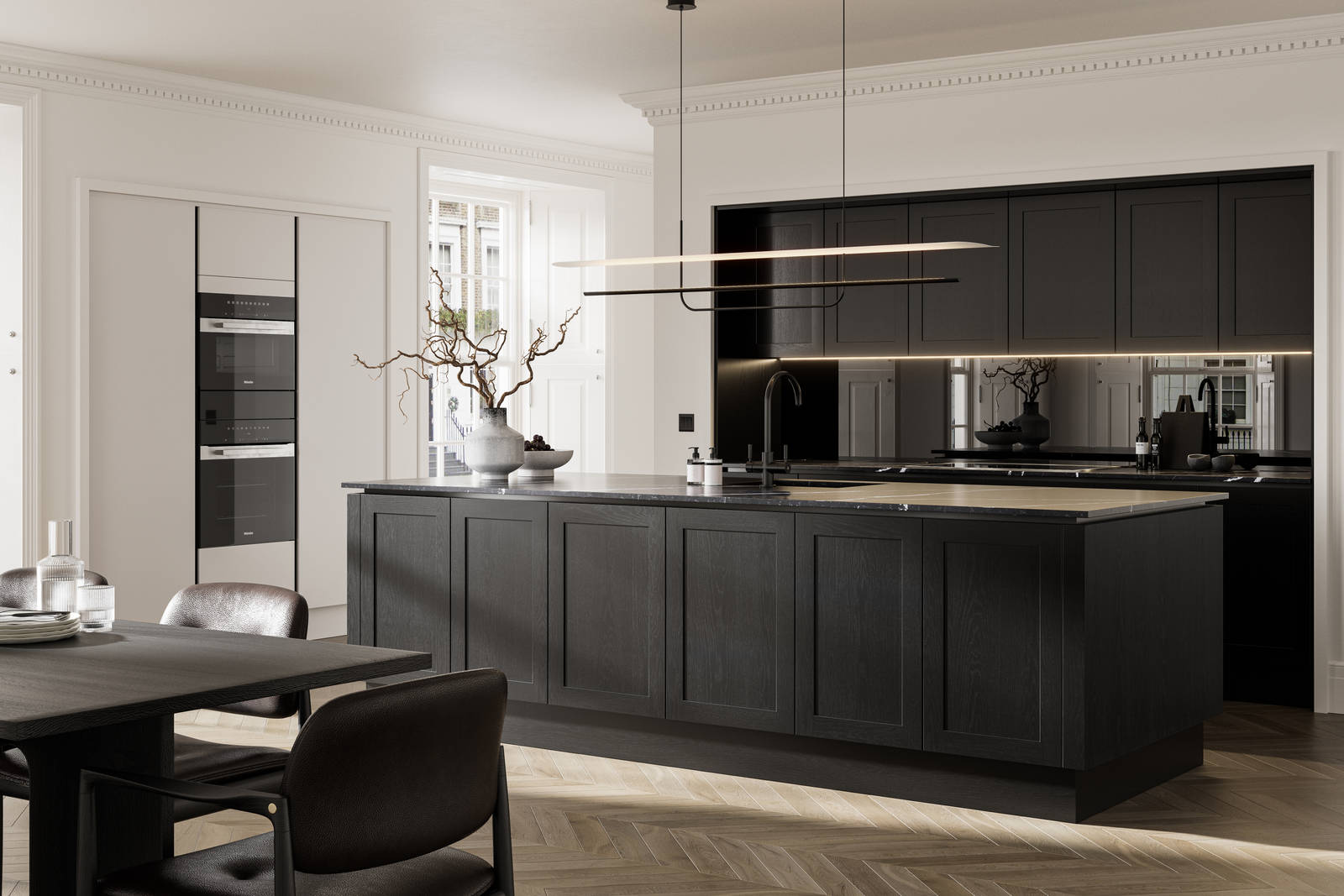 Handleless frame doors Integra Wardley Sumi black kitchen with kitchen island, Integra Soho Limestone tall cabinets with integrated ovens, black dining table and chairs, pale oak chevron flooring.