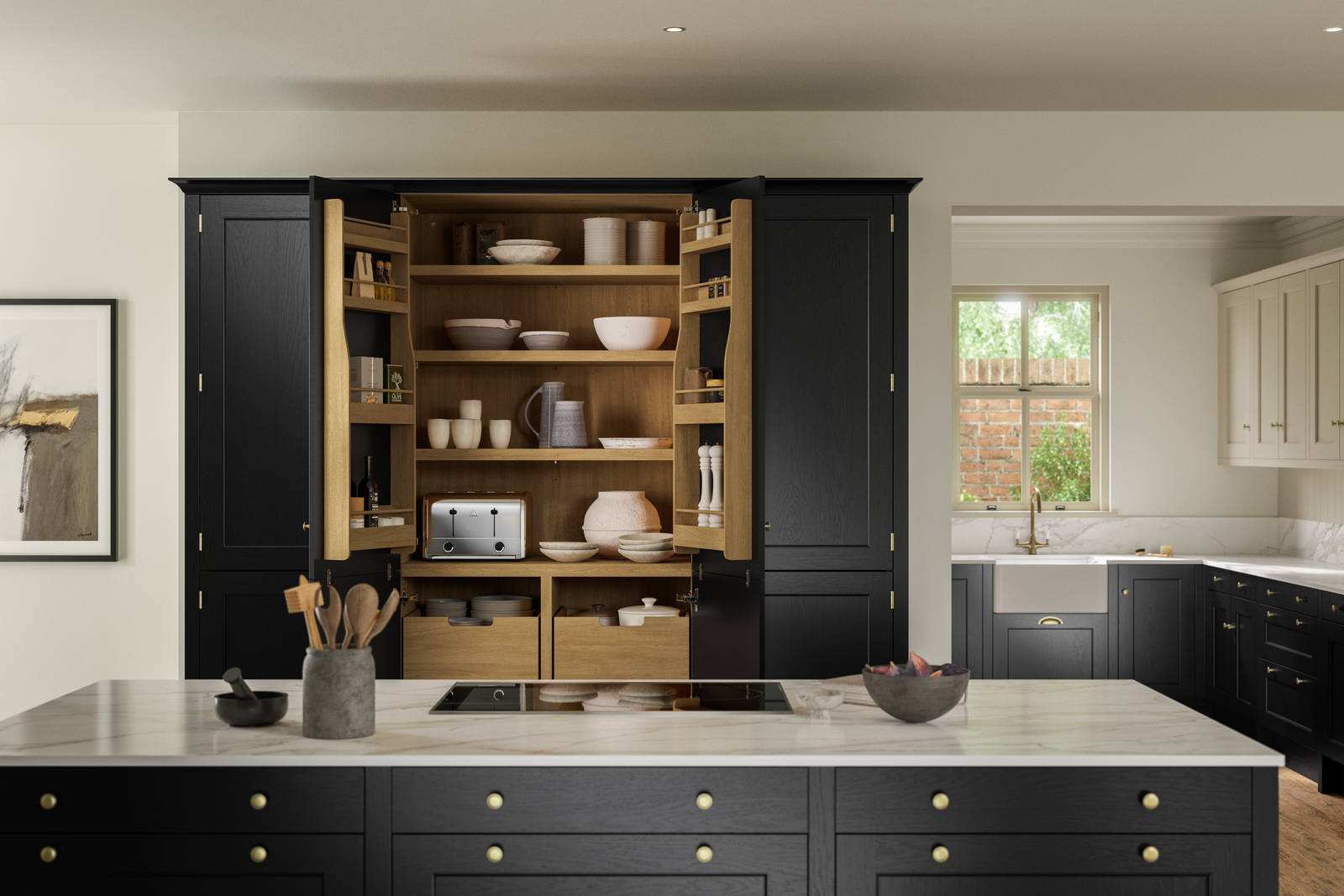 View over kitchen island in Traditional Shaker-style tactile woodgrain Ludlow Sumi Black kitchen, opened tall oak larder cabinets, brass accessories, marbled white and grey worktop, white ceramic sink and brass tap.