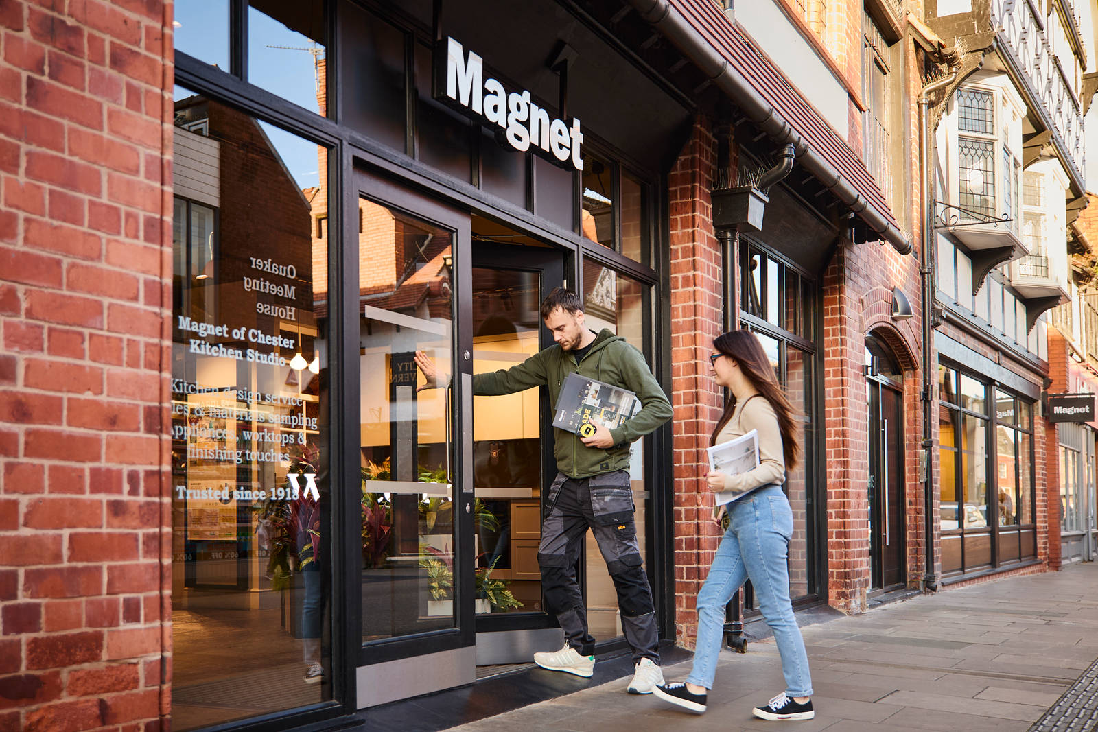 Man dressed in workwear and woman in plain clothes entering Magnet Store