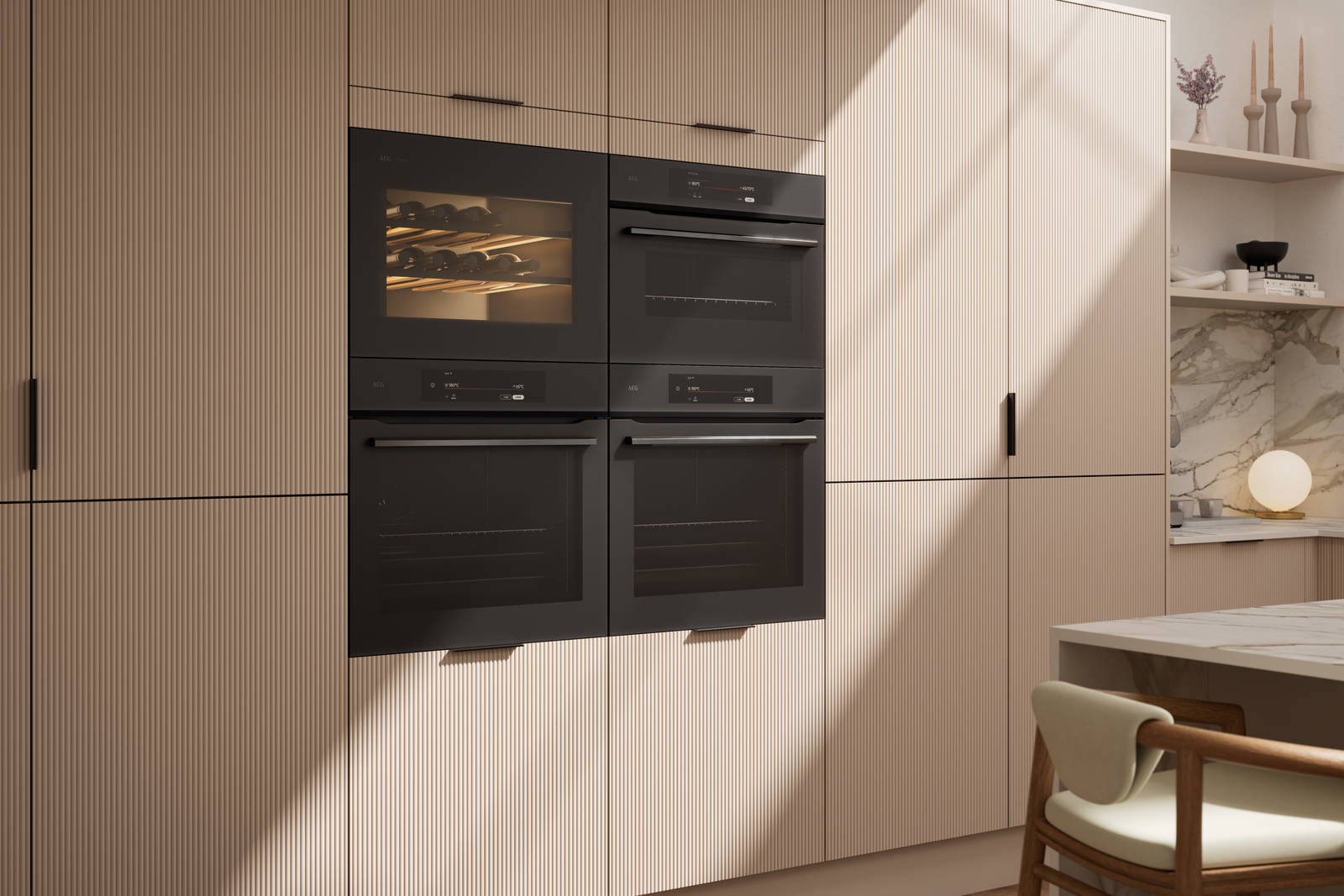 Fluted front kitchen Reed from Magnet in light warm neutral shade Shell, tall cabinets with appliances like ovens and a wine cooler, black handles