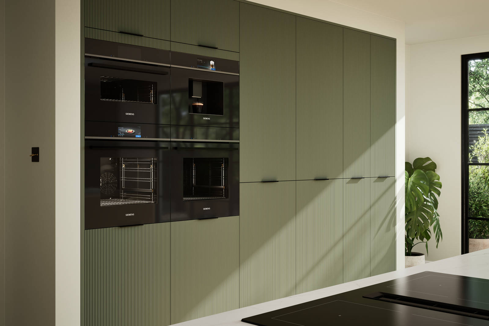 Green fluted kitchen fronts on tall cabinets with built-in appliances and black handles.