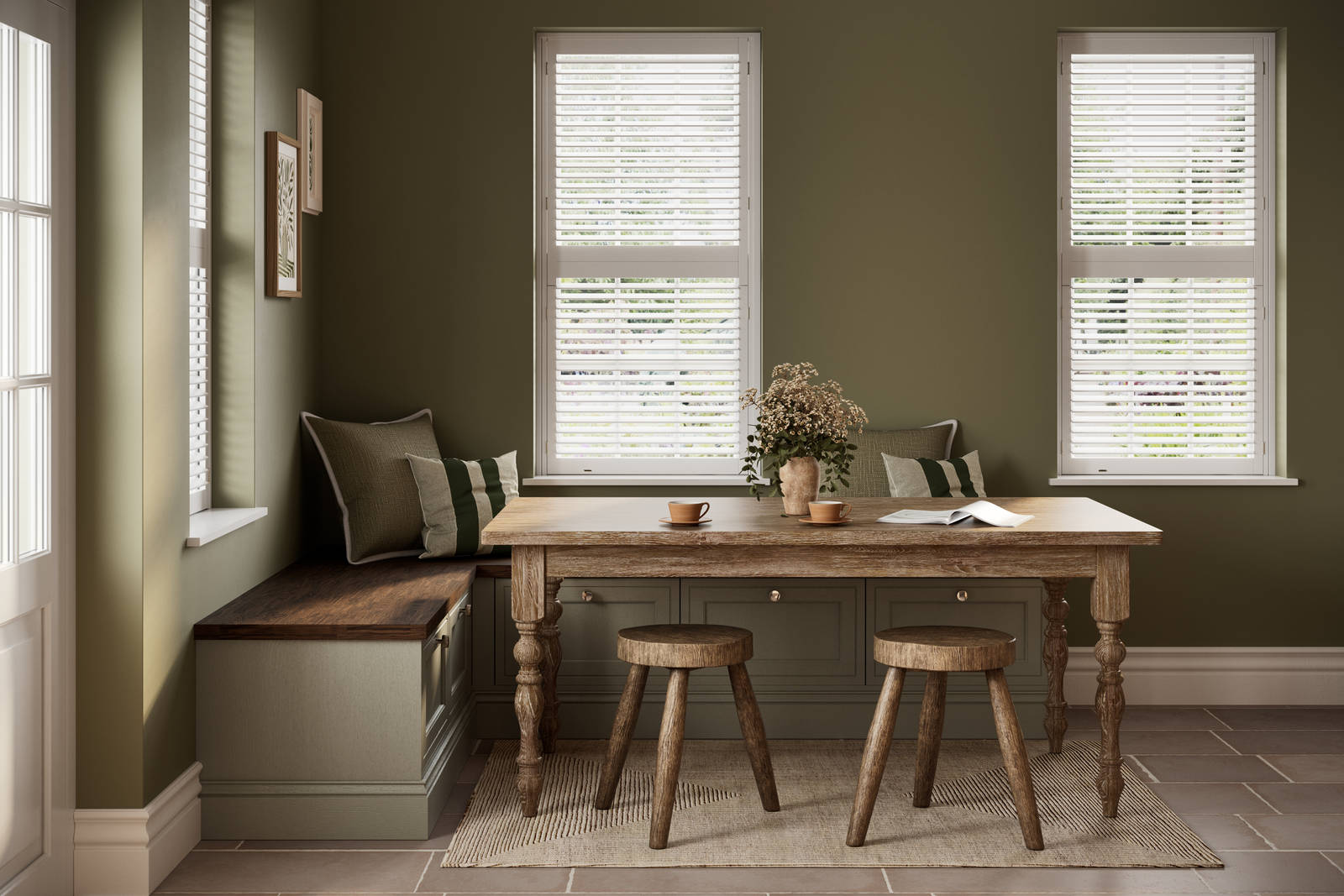 Dining area with low Shaker style painted wood grain cabinets Bewdley cabinets as a bench with a wooden table and stools in a room with painted green walls.