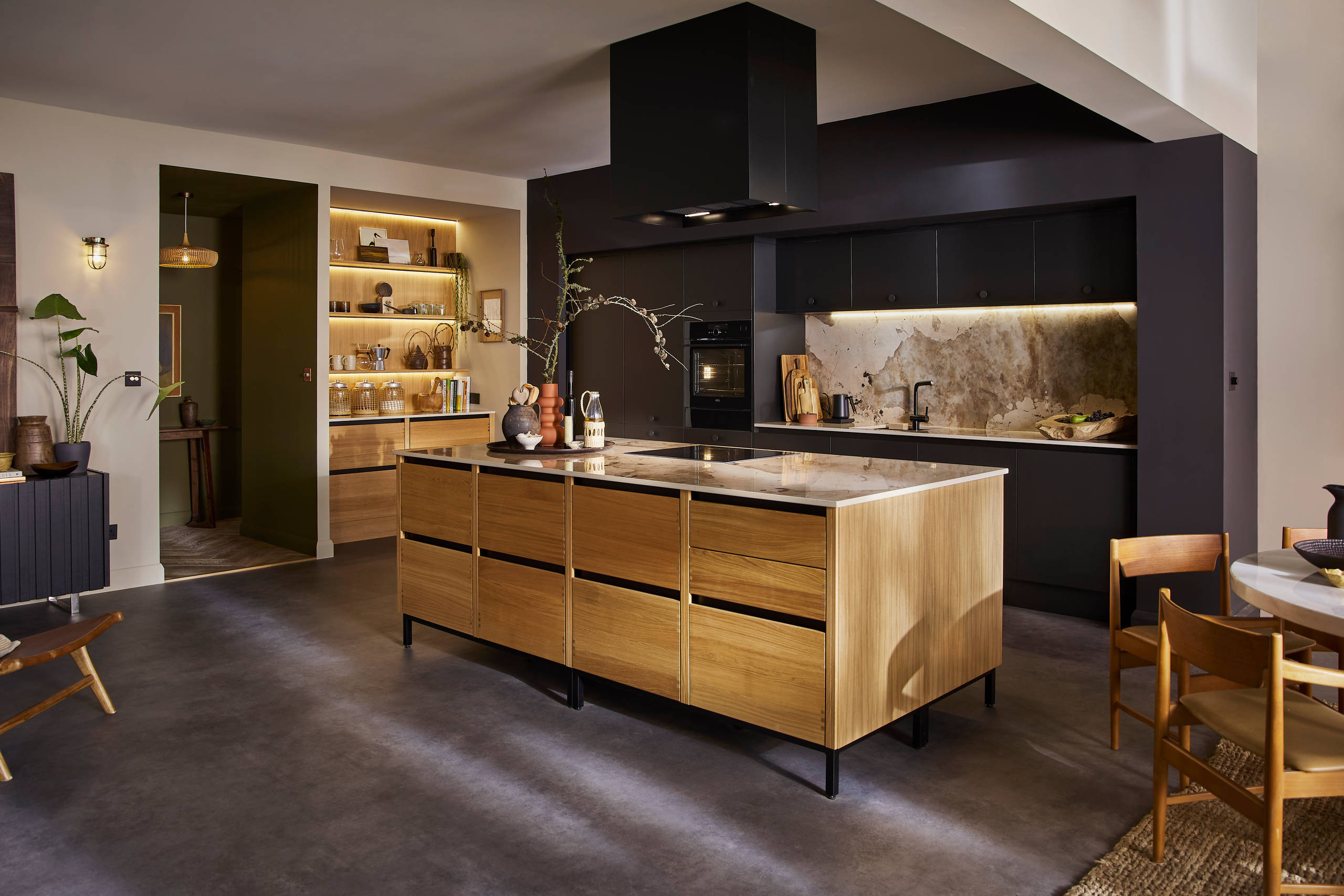 View of natural oak Nordic Craft kitchen island contrasting against the dark Sumi Black Hoxton cabinetry behind it.