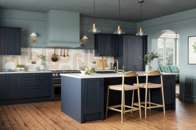 Modern country-style Ludlow kitchen in dark blue shade Midnight, with lighter blue walls, wooden floors and wooden barstools by kitchen island.