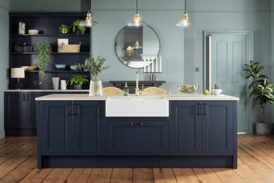 Modern country-style kitchen island with Shaker door Ludlow in dark blue shade Midnight, a porcelain sink, marbled worktop, brass tap and open shelves in matching blue.