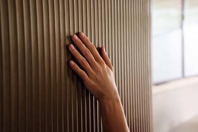 Close-up of hand touching the fluted wood fronts in Magnet's kitchen Nordic Nature.