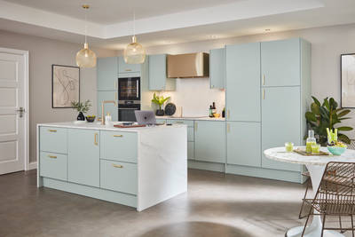 Light open plan Soho kitchen in Seagrass shade with brass tap, handles and other accent details
