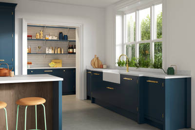 Corner view of Soho Voyage Blue kitchen white porcelain wink, brass tap and matching brass handles.