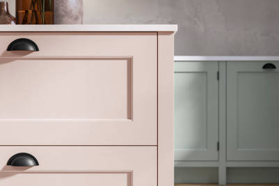 Closeup of Ludlow kitchen island, in a light pink colour with black accent handles.