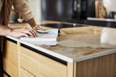 Close-up of Nordic craft kitchen island, with a beautiful marbled worktop as someone is checking a recipe in a cook book.