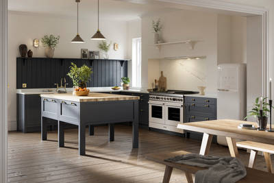 View of full shaker kitchen, dark blue cabinetry in shade Midnight, decorated with plants and framed photos.
