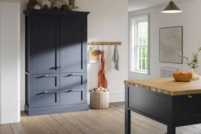 Tall shaker cabinet in dark blue shade, with handmade ceramics on top.