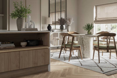 Integra Ascoli kitchen, close-up view of kitchen island with dining table in background. Light and earthy toned interior with plants.