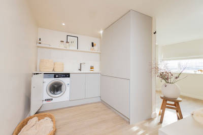 A utility room with cabinets with beige slab fronts in Yasmin Wyatt's calm and contemporary home with Luna Pebble from Magnet.