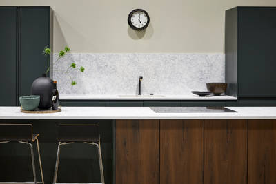 The modern Duxbury kitchen in Arboretum, paired with a wood-effect kitchen island, white worktop and splashback and accessorised with natural accents.
