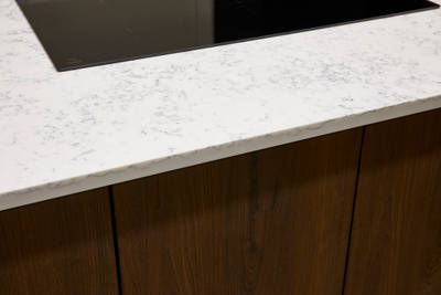 Wooden kitchen cabinets paired with white marble-effect worktop and modern glass hob.