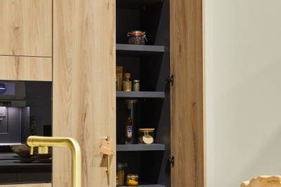 Magnet's modern Portobello kitchen in a light woodgrain décor, larders with a sleek grey interior.