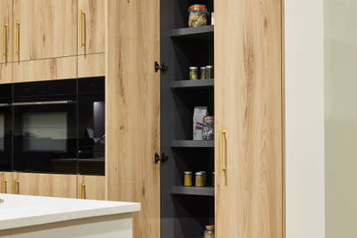 Magnet's modern Portobello kitchen in a light woodgrain décor, larders finished with brass bar handles.