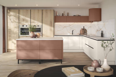 Integra Portobello Bosco as tall cabinets with integrated Samsung Ovens, white handleless Integra Soho cabinetry and a kitchen island in the shade Baked Clay, matching top cabinets and the beautiful fan above hob, all decorated with earth tone ceramics and plants.