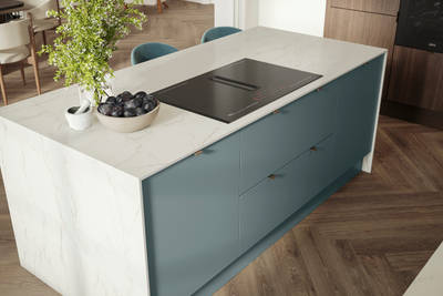 Overhead view of kitchen island with marbled dekton worktop, integrated hob and Soho Duck Blue cabinetry from Magnet.