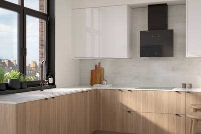Ascoli kitchen from Magnet with Natural Oak cabinetry, a white worktop, Ascoli Gloss white wall cabinets over countertop paired with matching black handles, tap, hood and window frame over white sink.