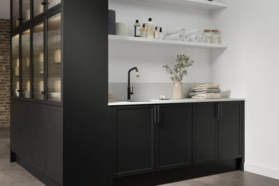 Laundry room sink area with open shelves for laundry detergents, a white Silestone Miami vena worktop and matching tall cabinets in kitchen area with fluted glass doors.