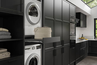 Pulled out drawer between laundry machine and dryer to serve as a shelf in black modern shaker Brunswick kitchen and laundry room